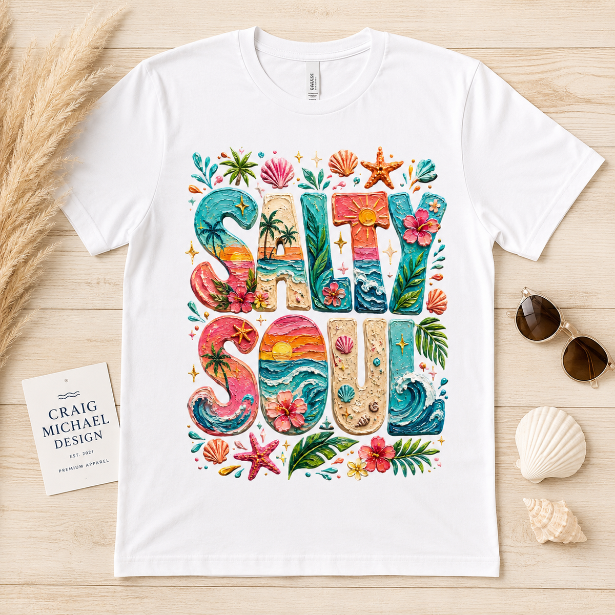 White t-shirt with "Salty Soul" in colorful, tropical-themed lettering.