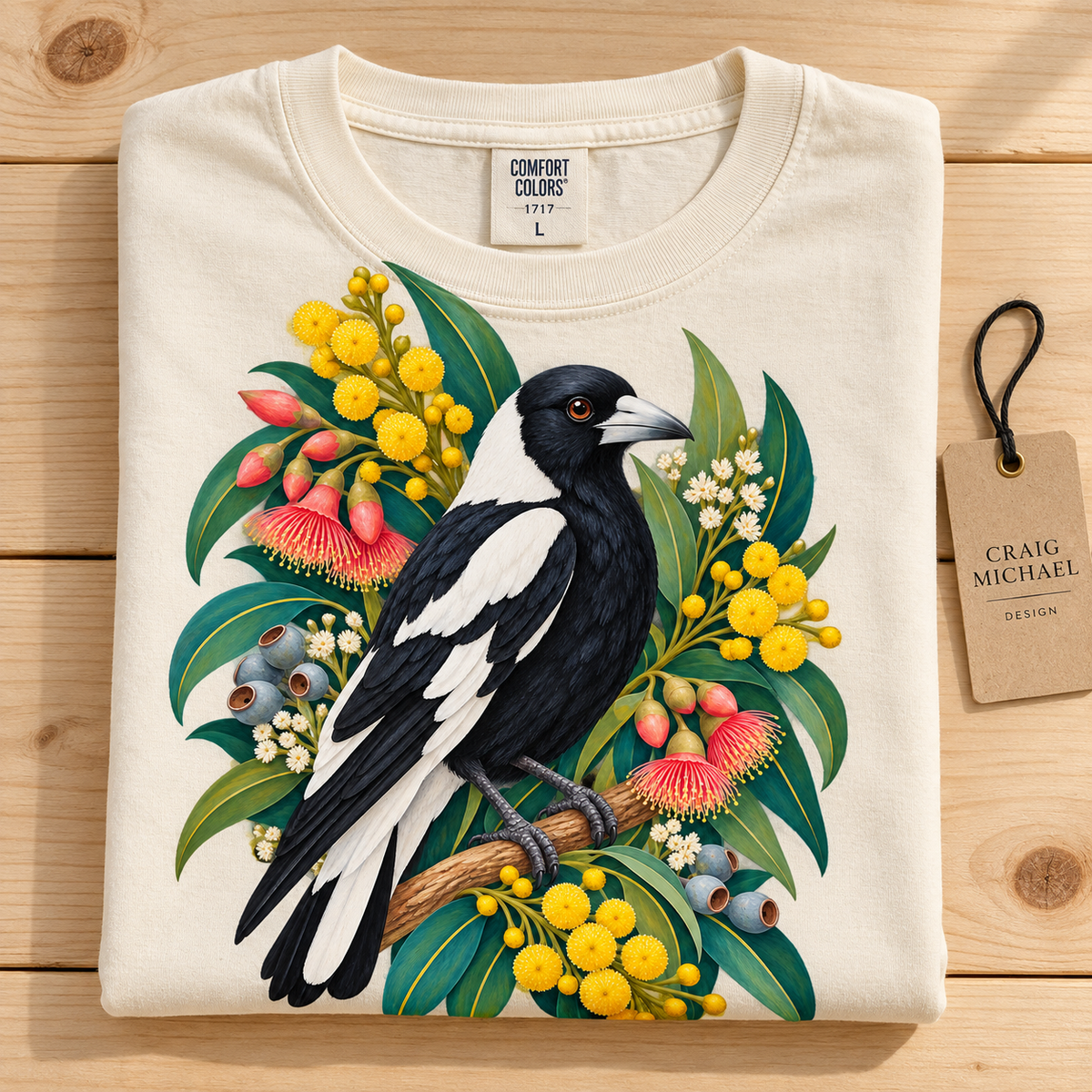 Cream t-shirt with a magpie, wattle flowers, and gum nuts design.