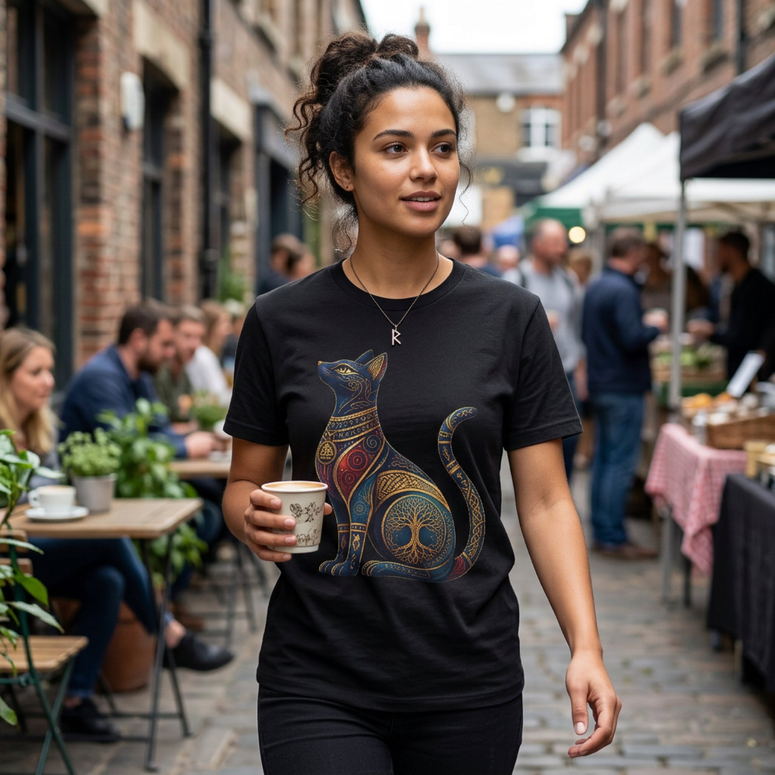 Woman in black t-shirt with intricate gold and blue cat tree of life design.