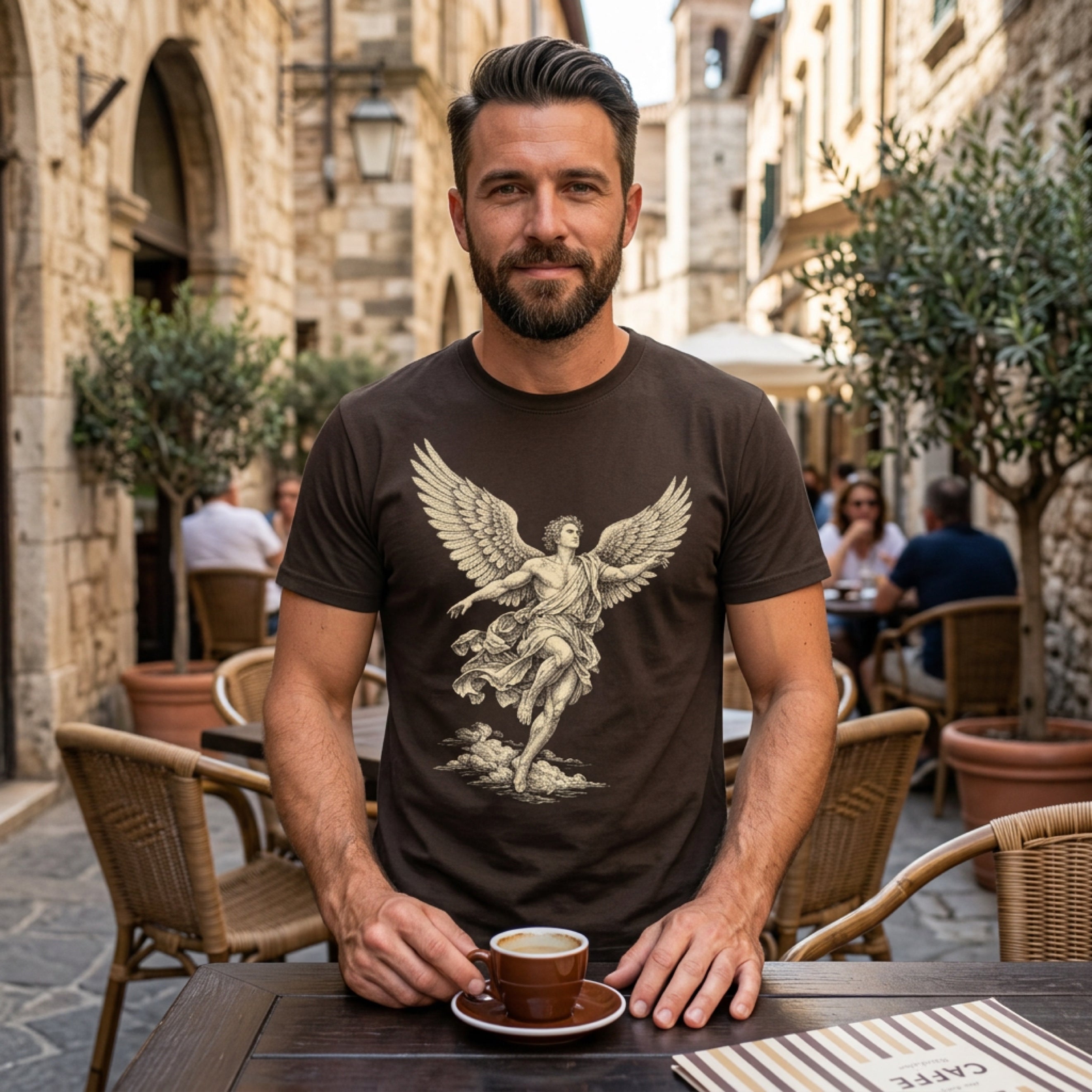 Man wearing a dark t-shirt with a winged figure design, holding a coffee cup.