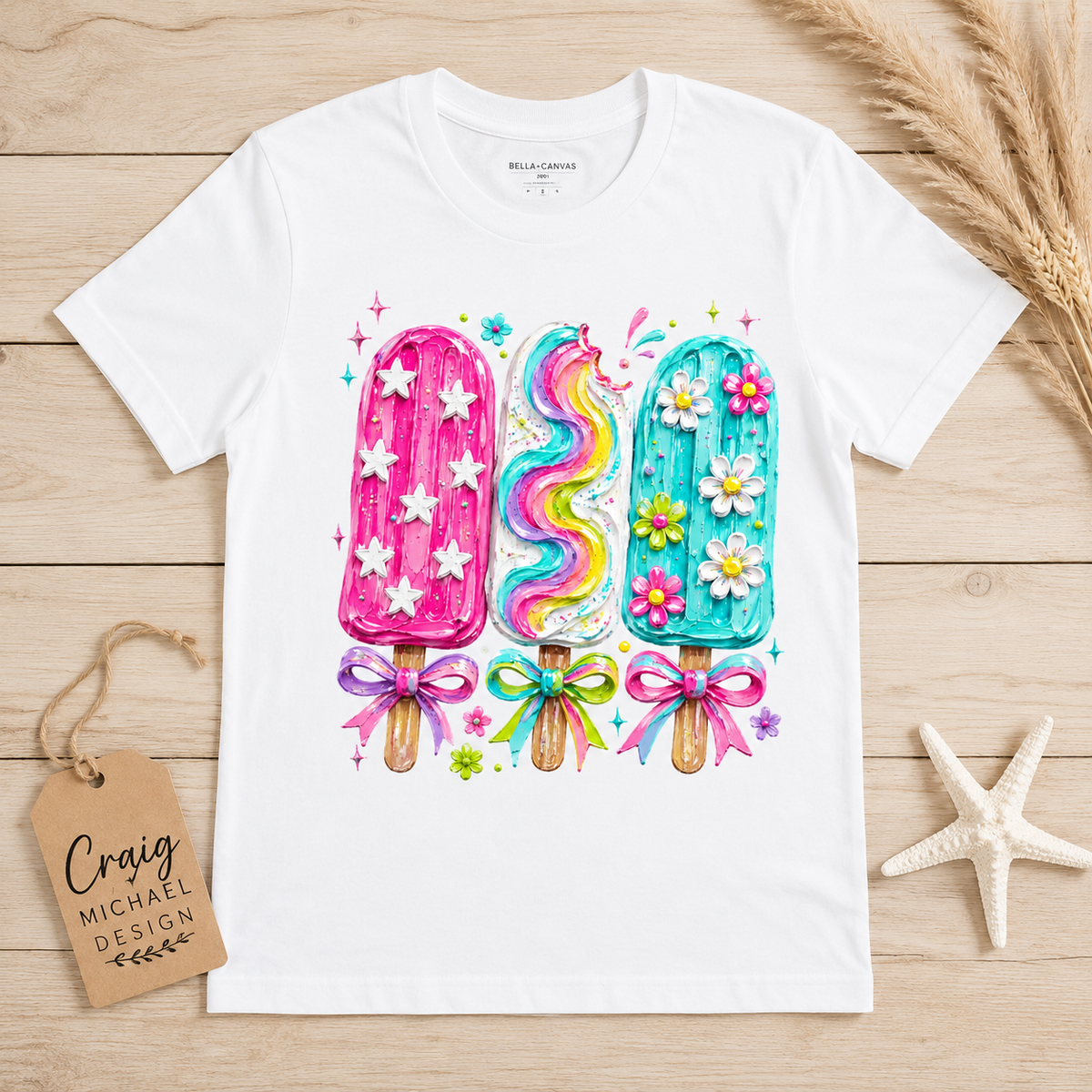 White t-shirt with cartoon popsicles, flowers, bows, and stars graphic.