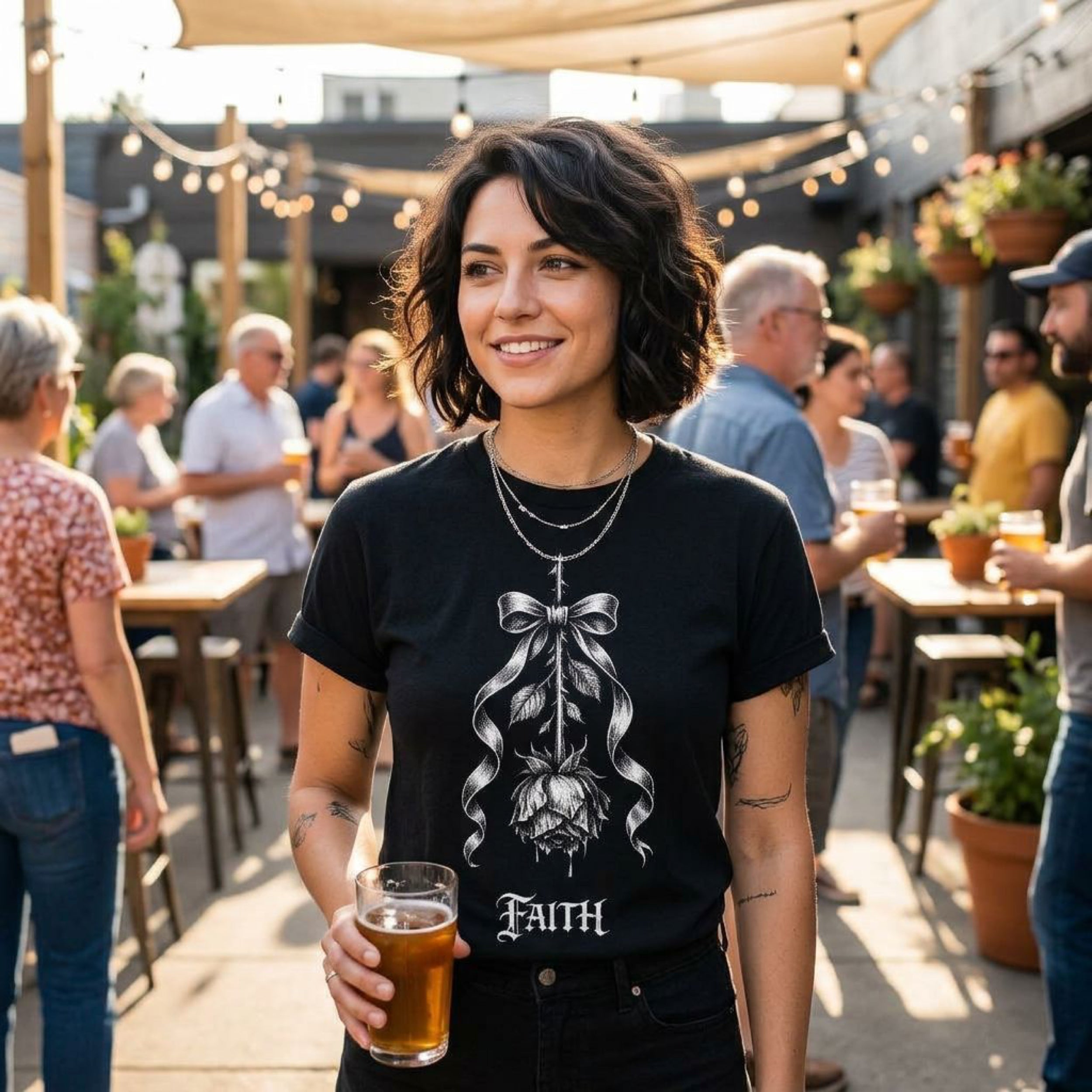 Woman wearing a black t-shirt with a rose and ribbon design, holding a beer.