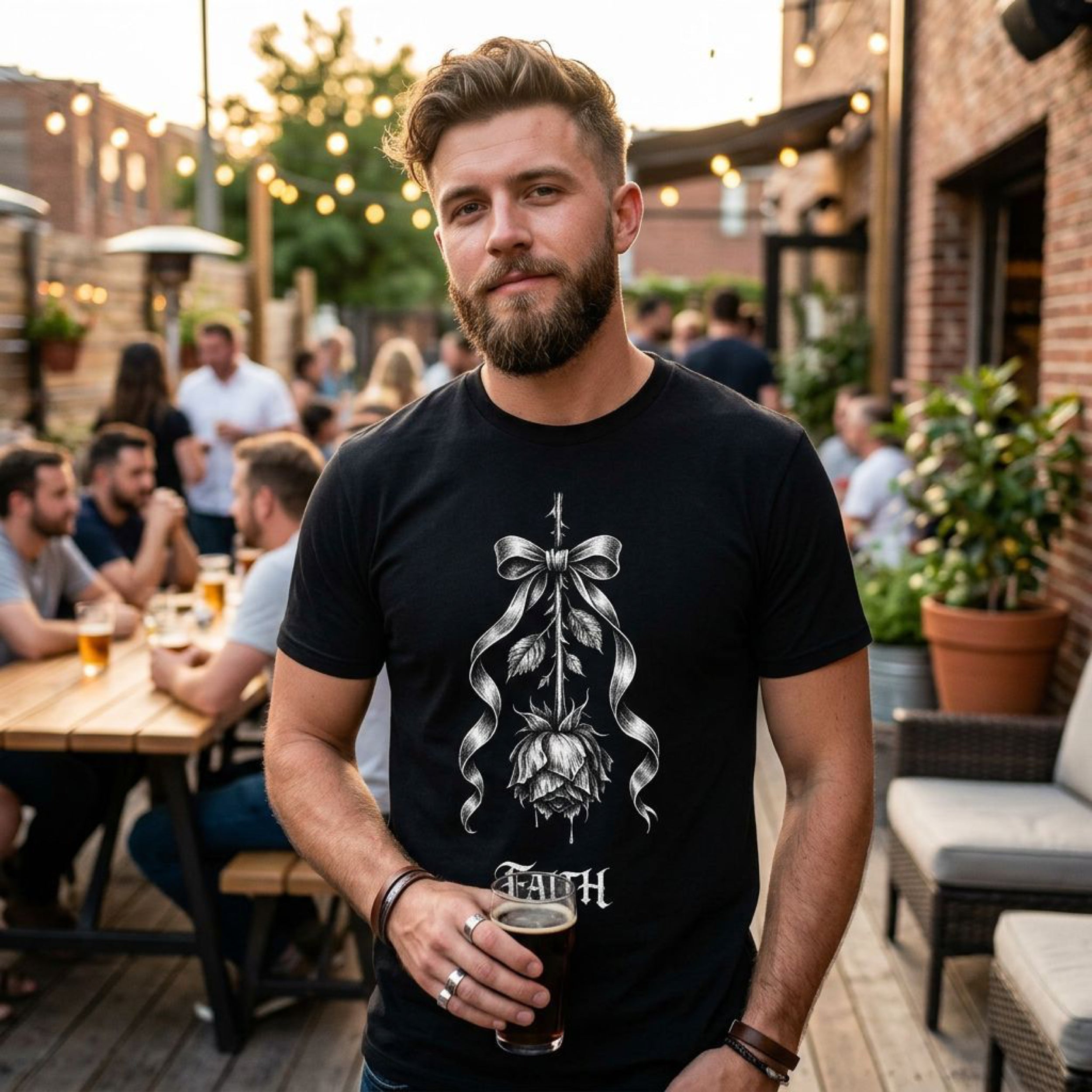 Man wearing black t-shirt with rose and ribbon graphic, holding glass of dark beer.
