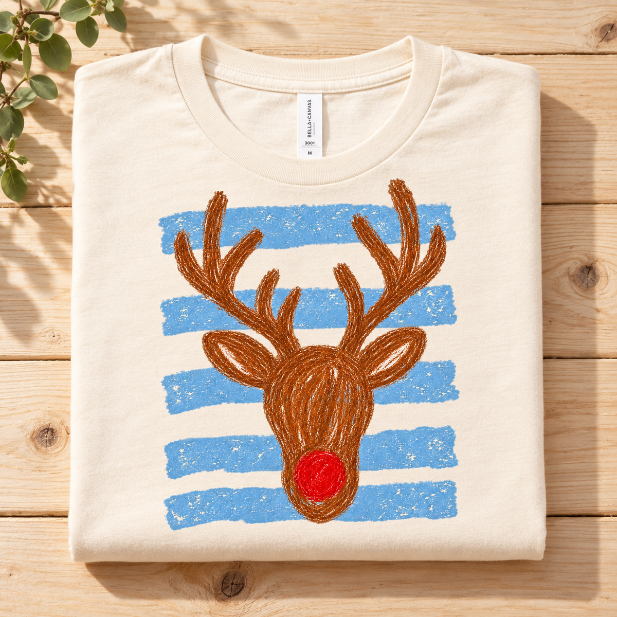 Cream t-shirt with a crayon-style drawing of a reindeer head and blue stripes.