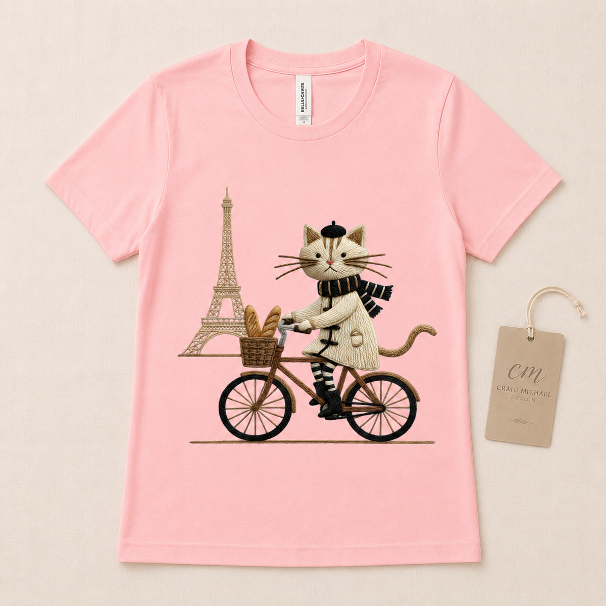 Pink t-shirt with a cat riding a bicycle in front of the Eiffel Tower.