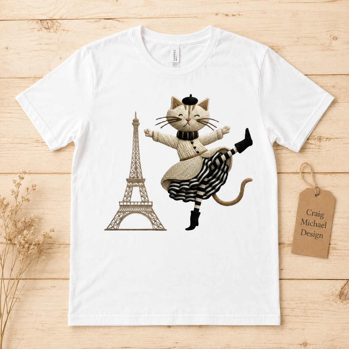 White t-shirt with a cartoon cat wearing a beret and a striped skirt, beside the Eiffel Tower.