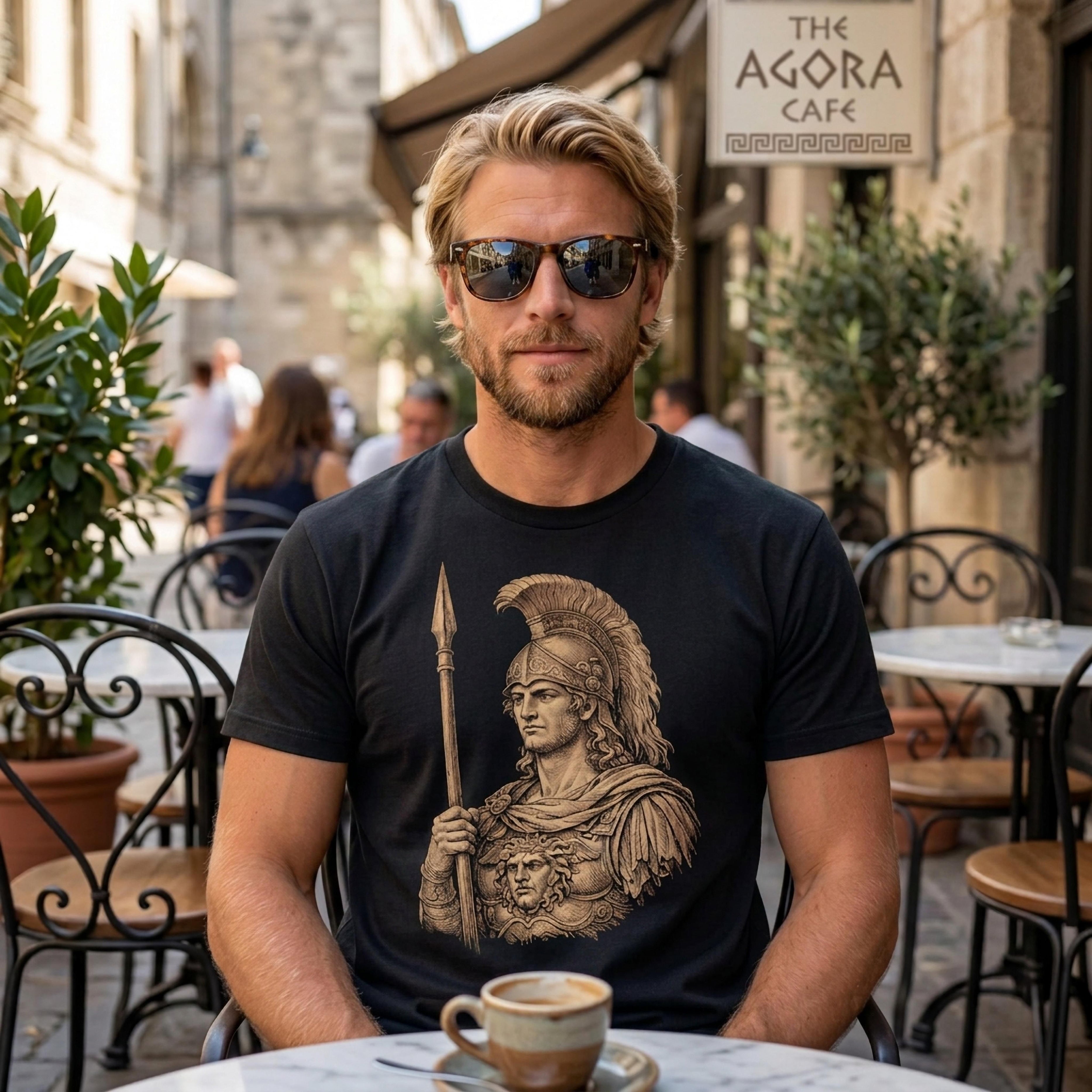 Man in t-shirt with ancient warrior graphic, sitting at cafe table.