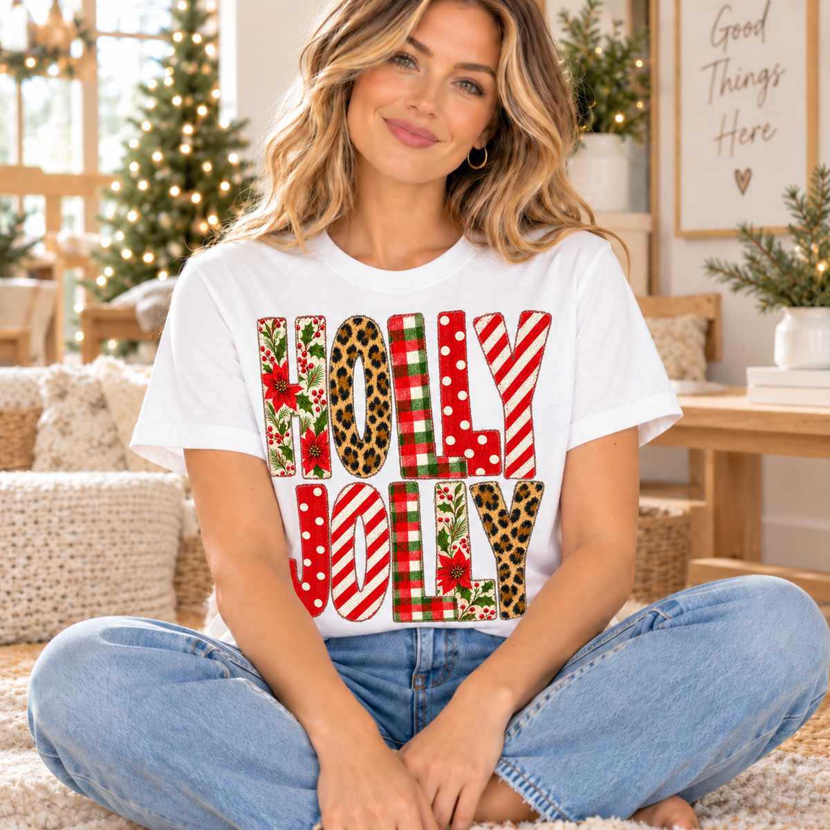White t-shirt with "HOLLY JOLLY" in festive patterns: poinsettias, plaid, leopard, stripes, and polka dots.