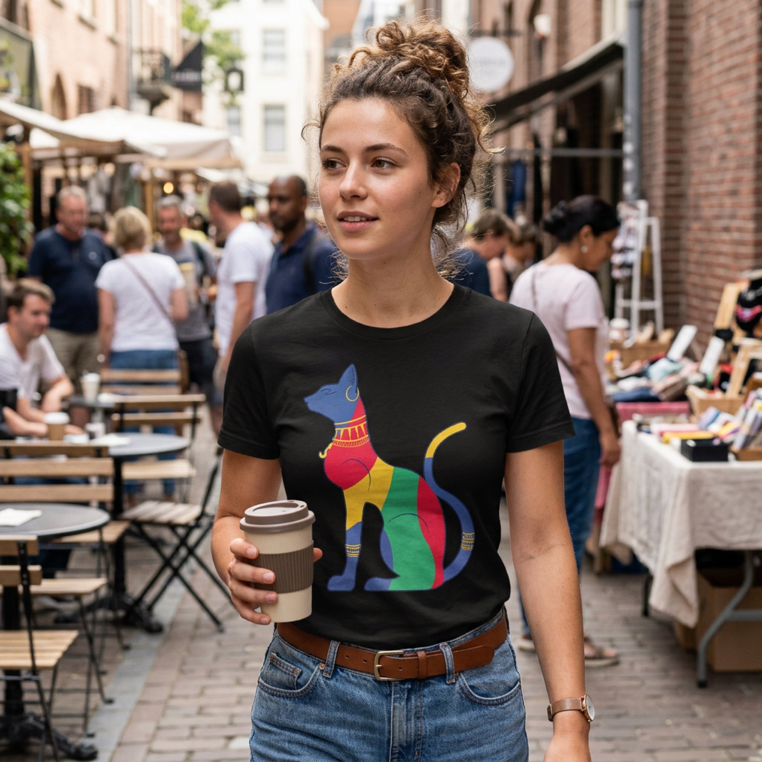 Woman in black t-shirt with colorful cat design holding a coffee cup.