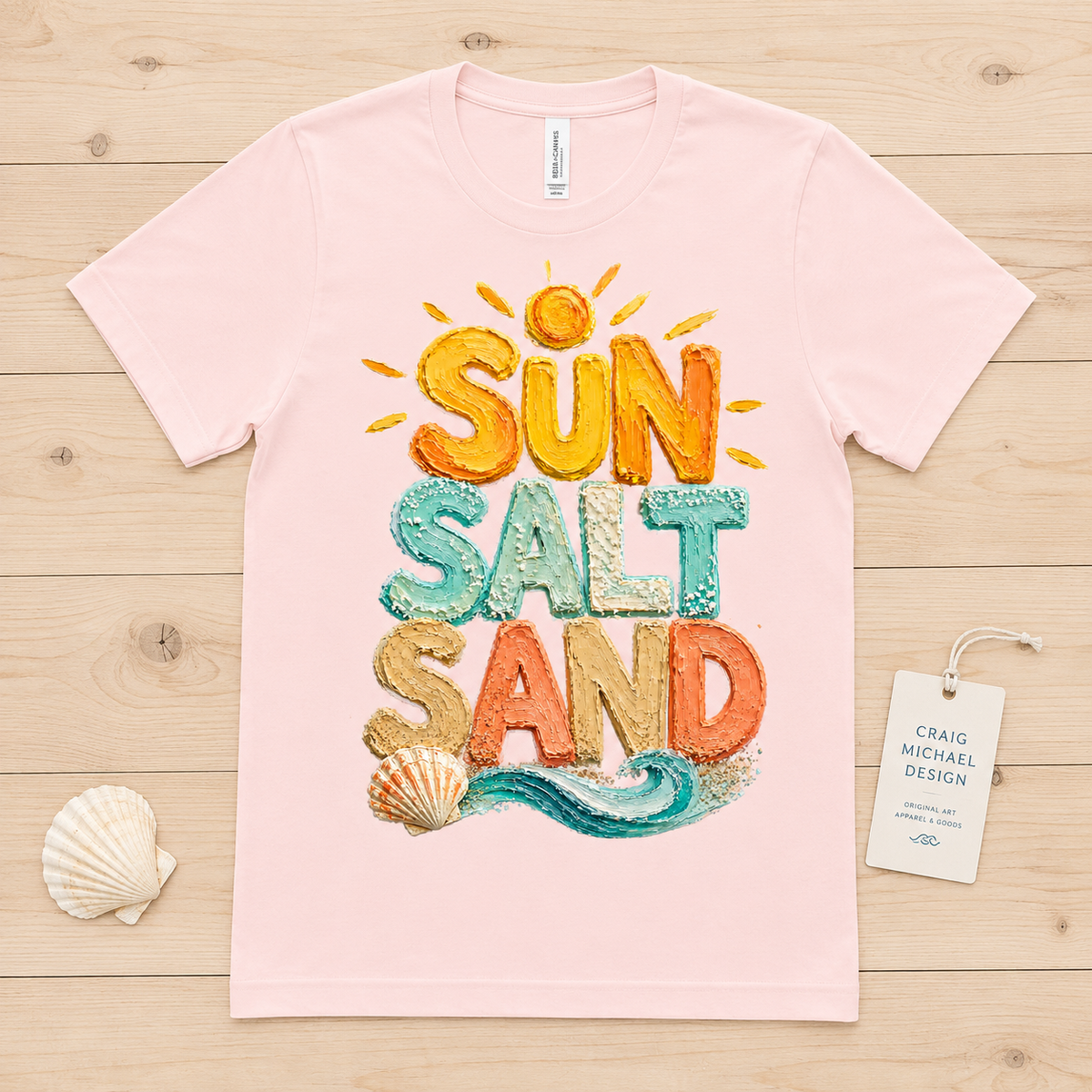 Pink t-shirt with colorful "Sun Salt Sand" text and beach elements.