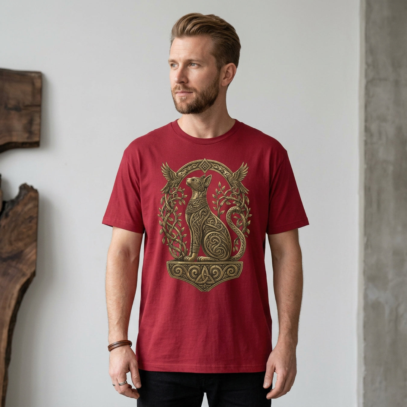 Man wearing maroon t-shirt with a golden cat and bird design.