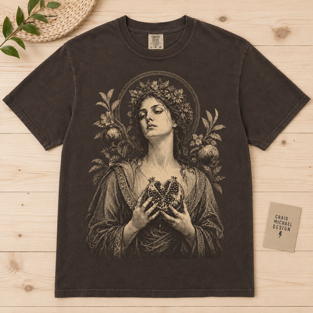 Dark t-shirt featuring woman with pomegranate and floral wreath.