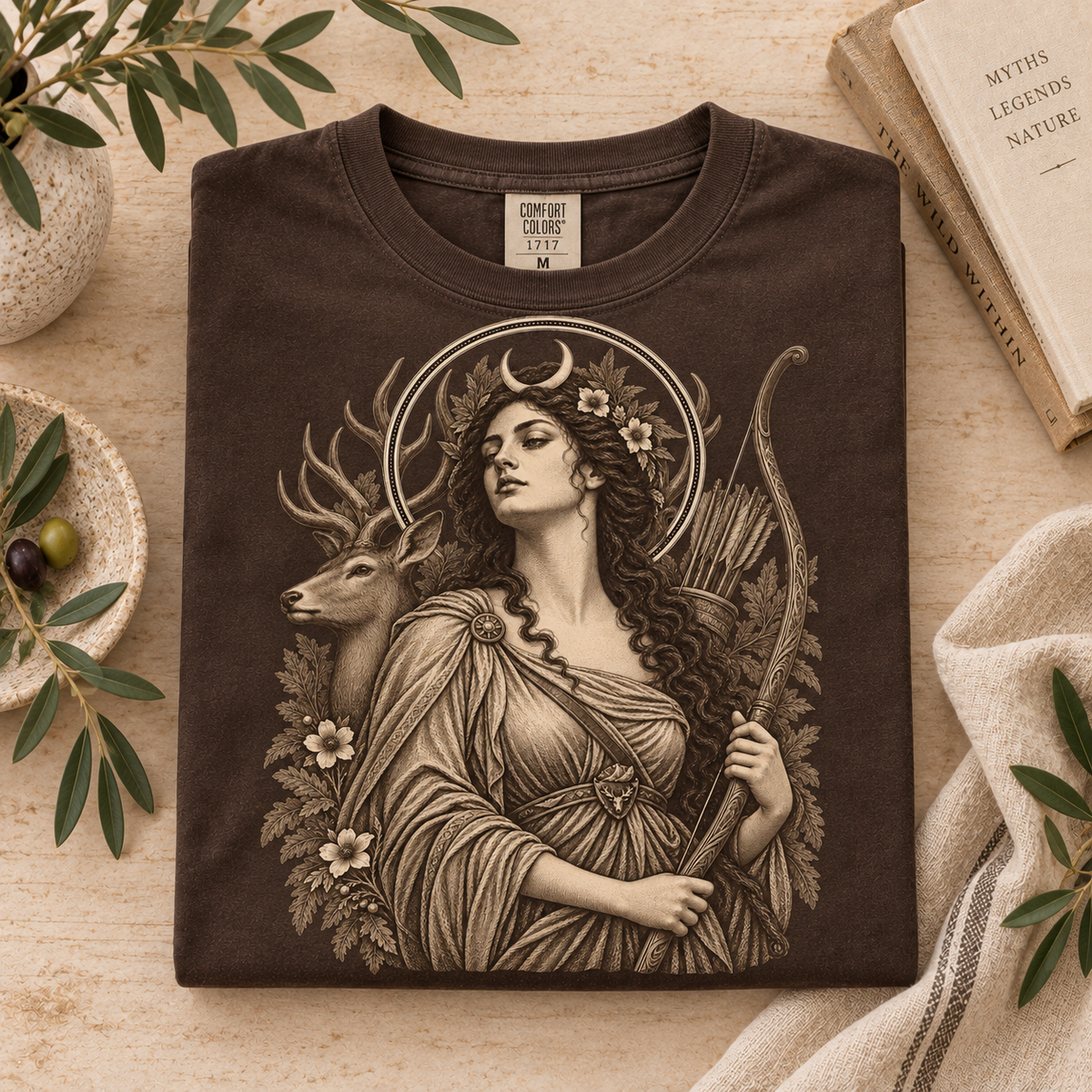 Brown t-shirt with Artemis graphic, featuring a woman with a crescent moon and bow, next to a deer.