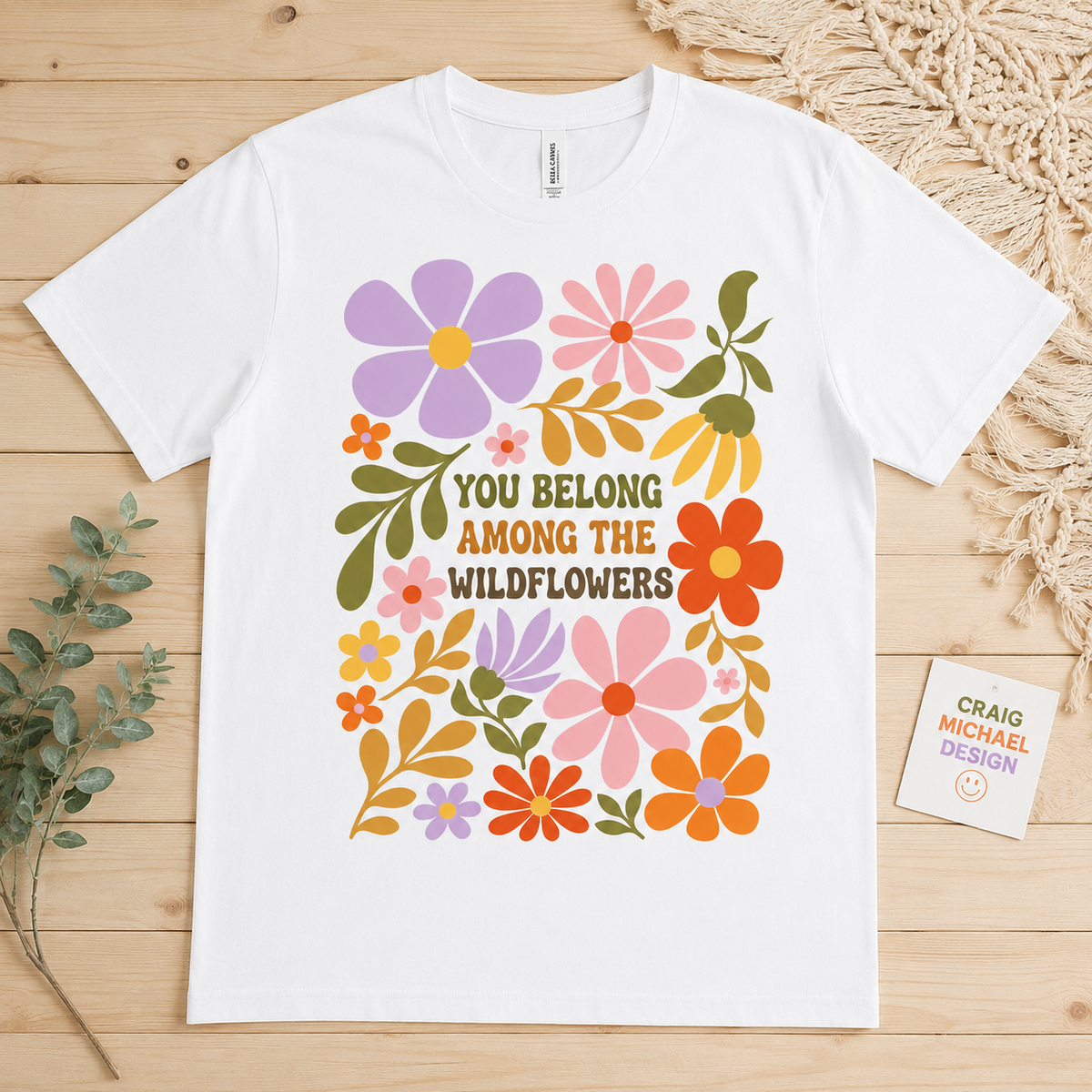 White t-shirt with colorful floral graphic and text "YOU BELONG AMONG THE WILDFLOWERS".