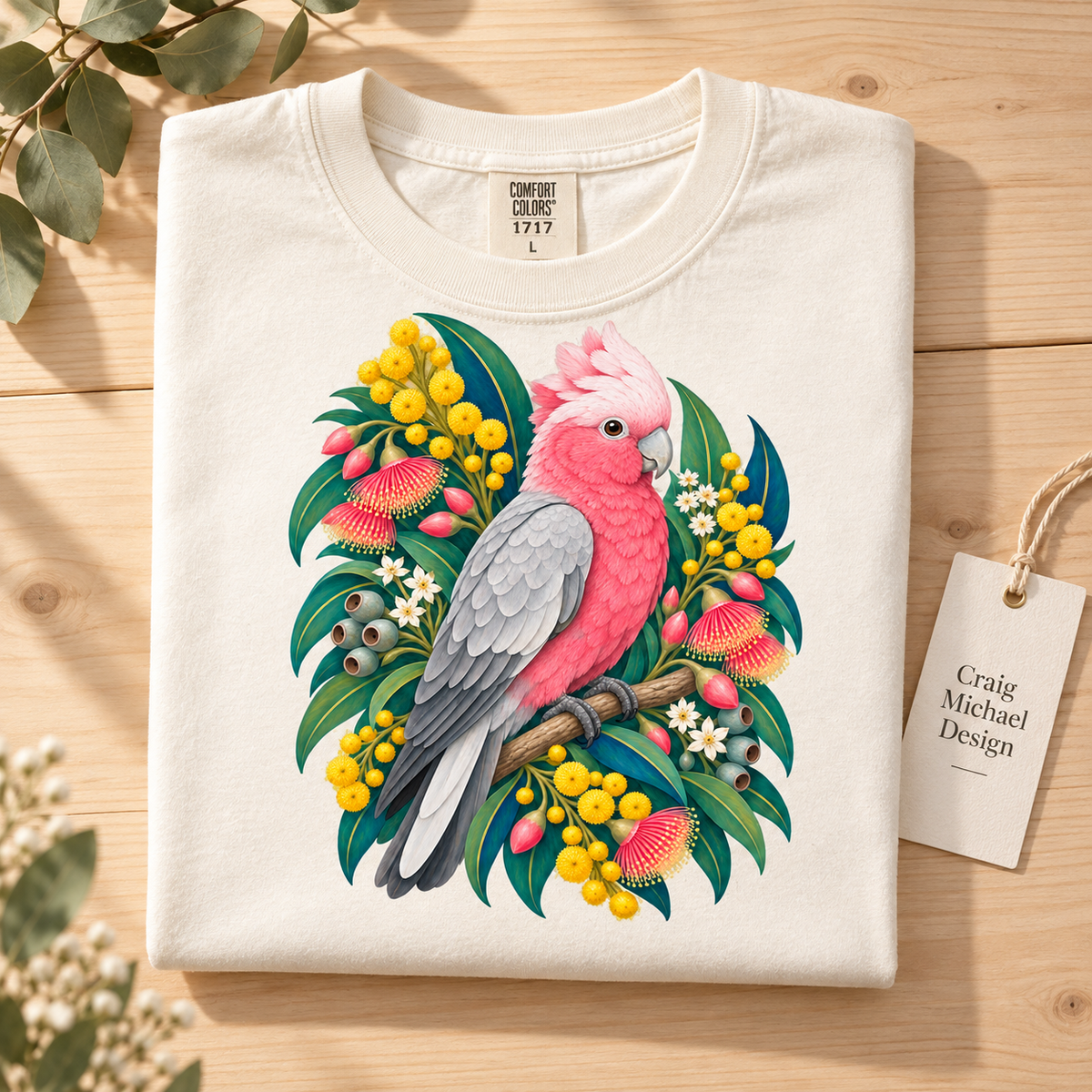 Cream t-shirt with pink and gray cockatoo art and floral accents.