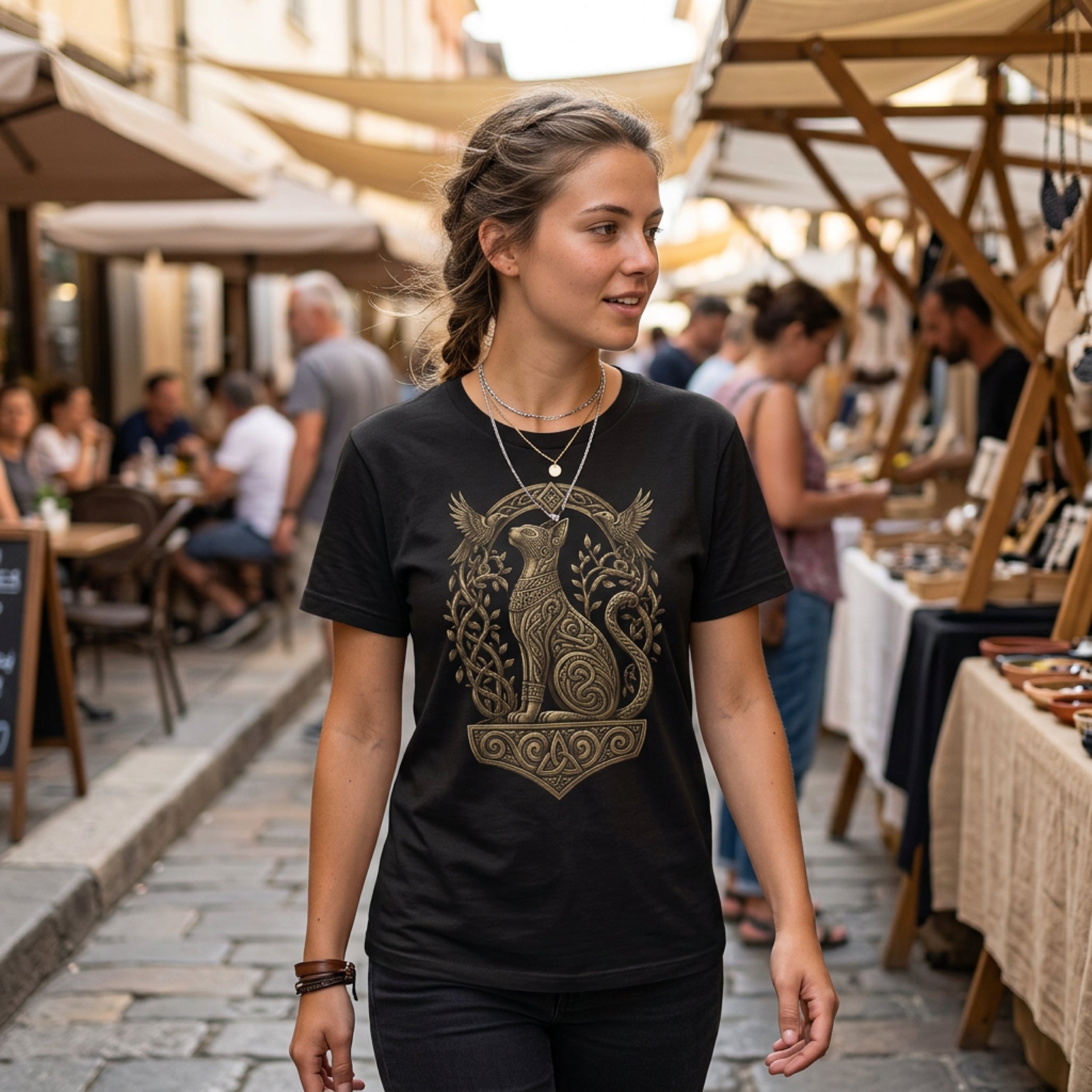 Woman wearing black t-shirt with gold Norse cat and knotwork graphic.