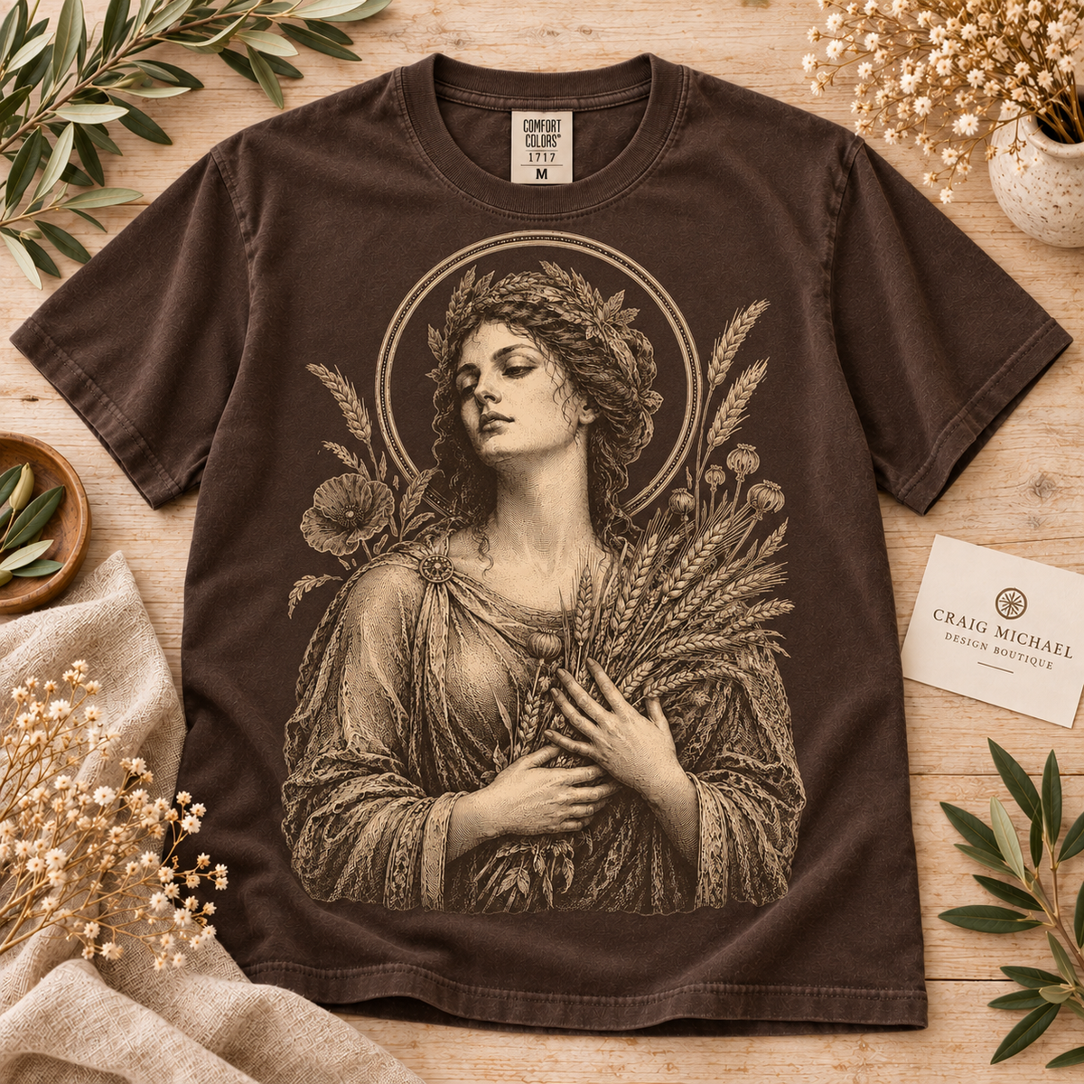 Brown t-shirt with sepia drawing of woman wearing laurel wreath holding wheat stalks.