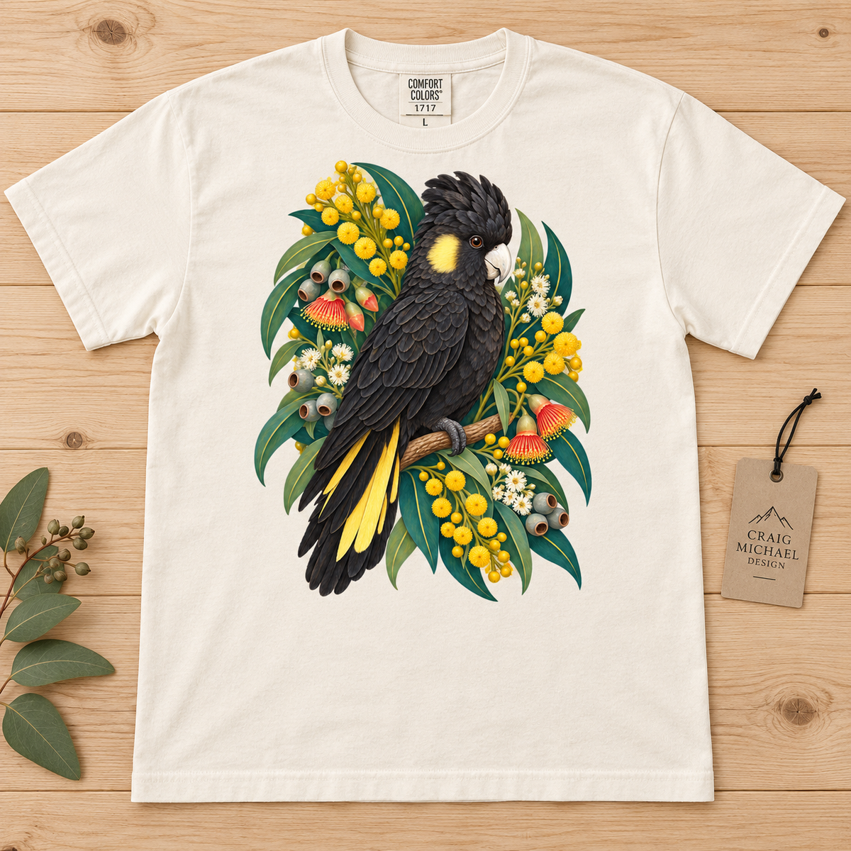 T-shirt with black cockatoo and eucalyptus branch artwork.