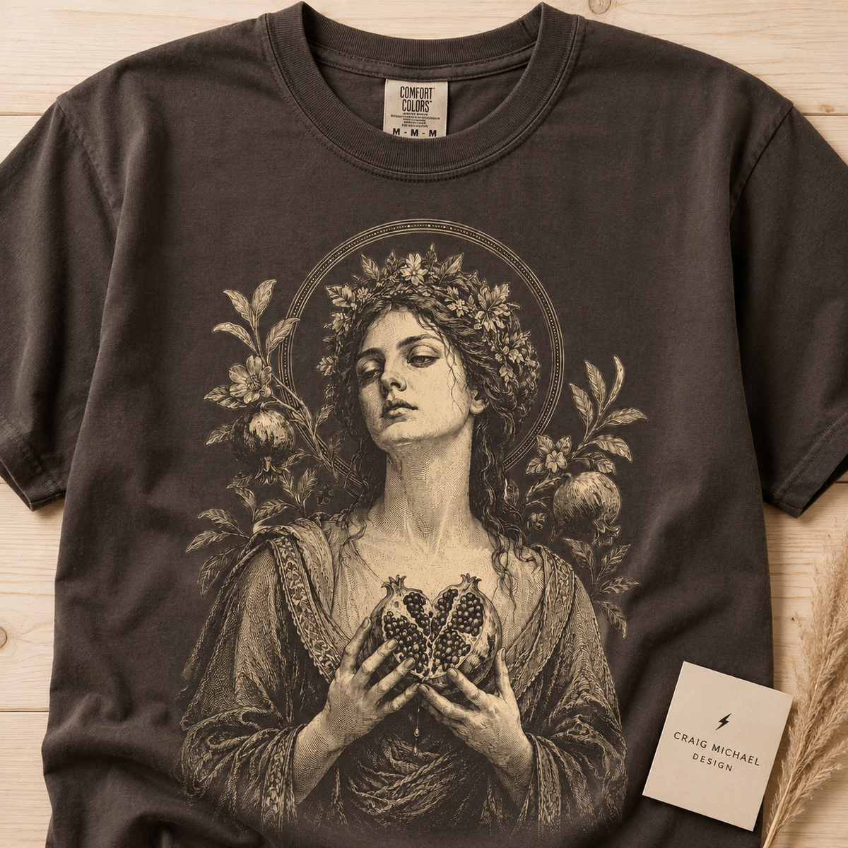 Dark t-shirt with illustration of a woman holding a split pomegranate heart.