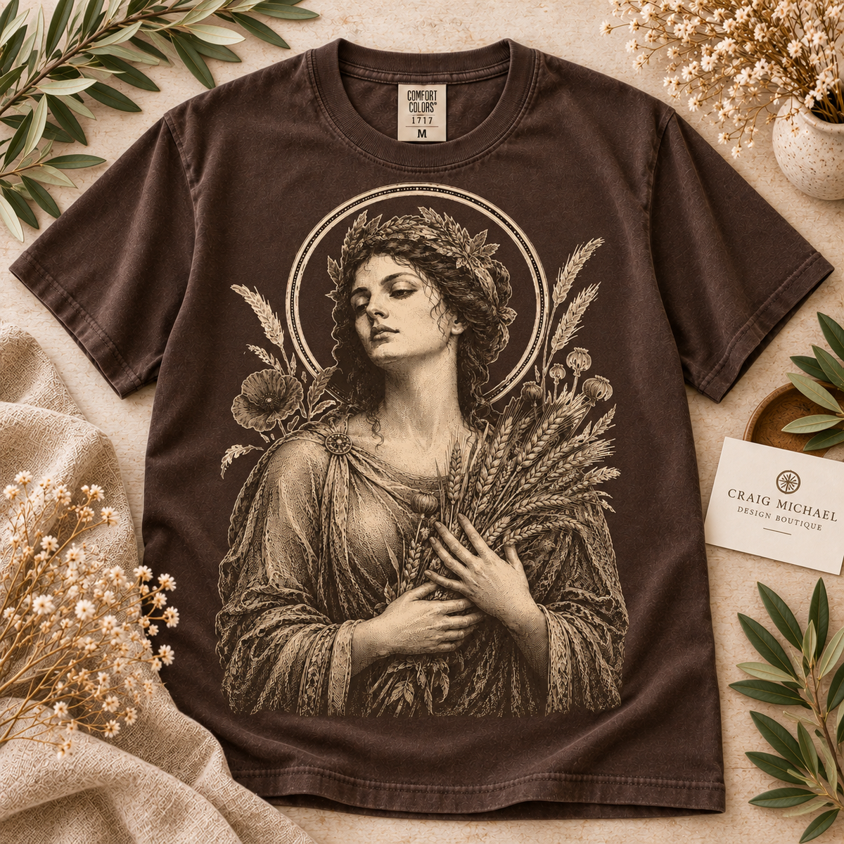 Brown t-shirt with vintage goddess illustration holding wheat and flowers.