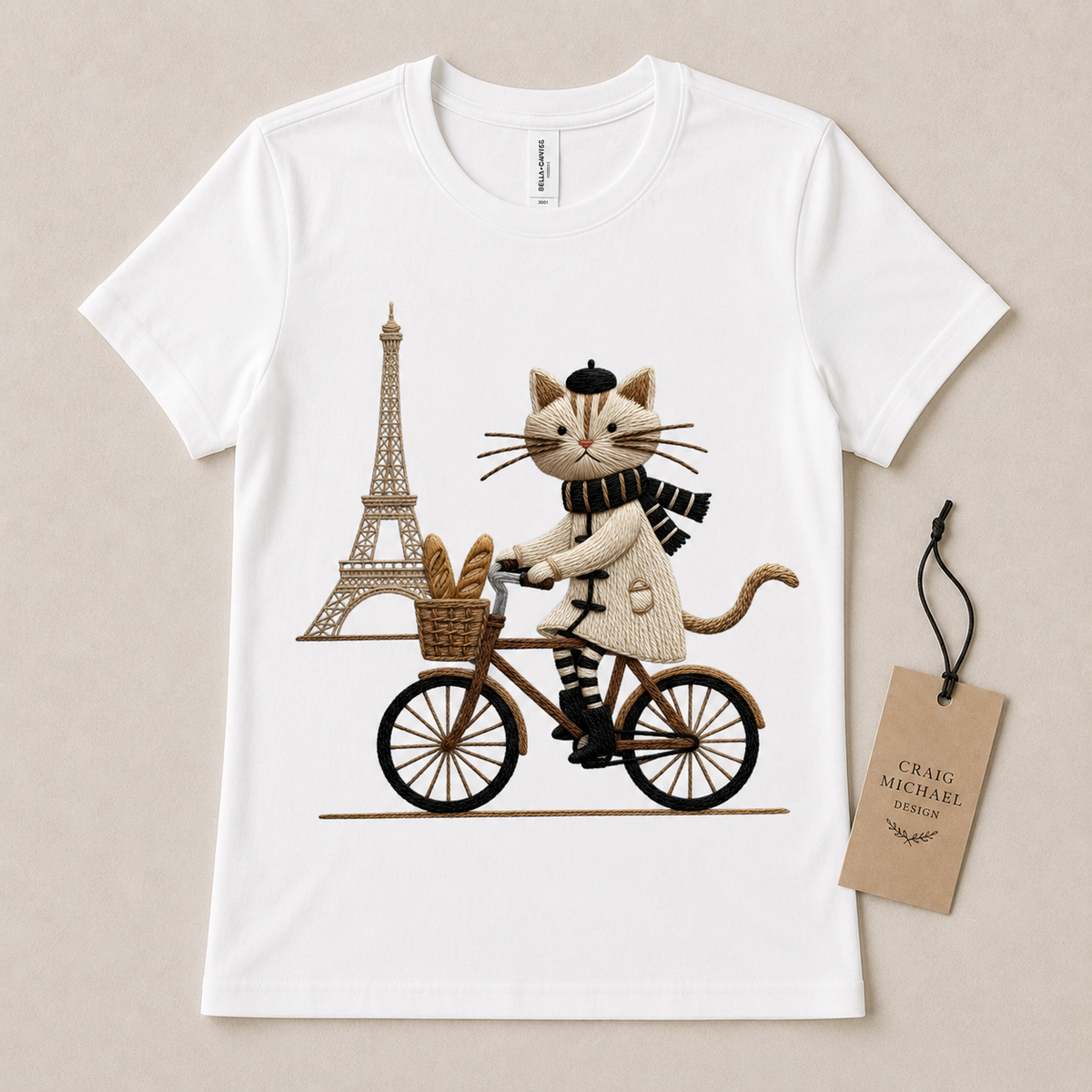 White t-shirt featuring a cartoon cat riding a bicycle with bread and the Eiffel Tower.