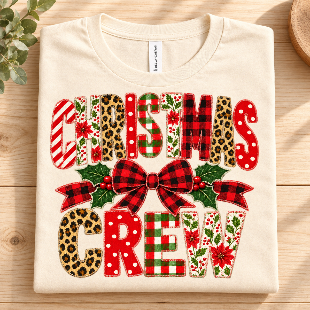 Cream t-shirt with "CHRISTMAS CREW" text in festive patterned letters and bow.