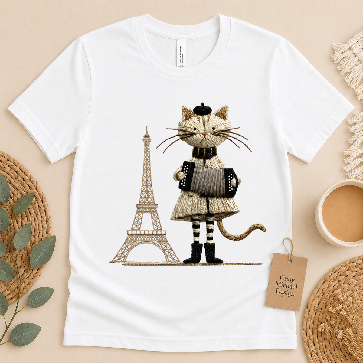 White t-shirt featuring a cartoon cat playing an accordion with the Eiffel Tower.