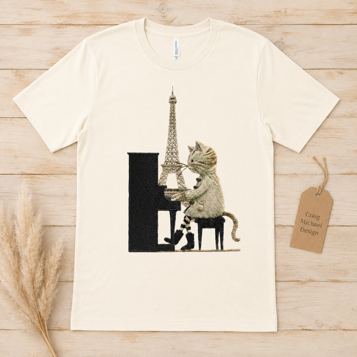Cat playing piano with Eiffel Tower behind on a cream t-shirt.