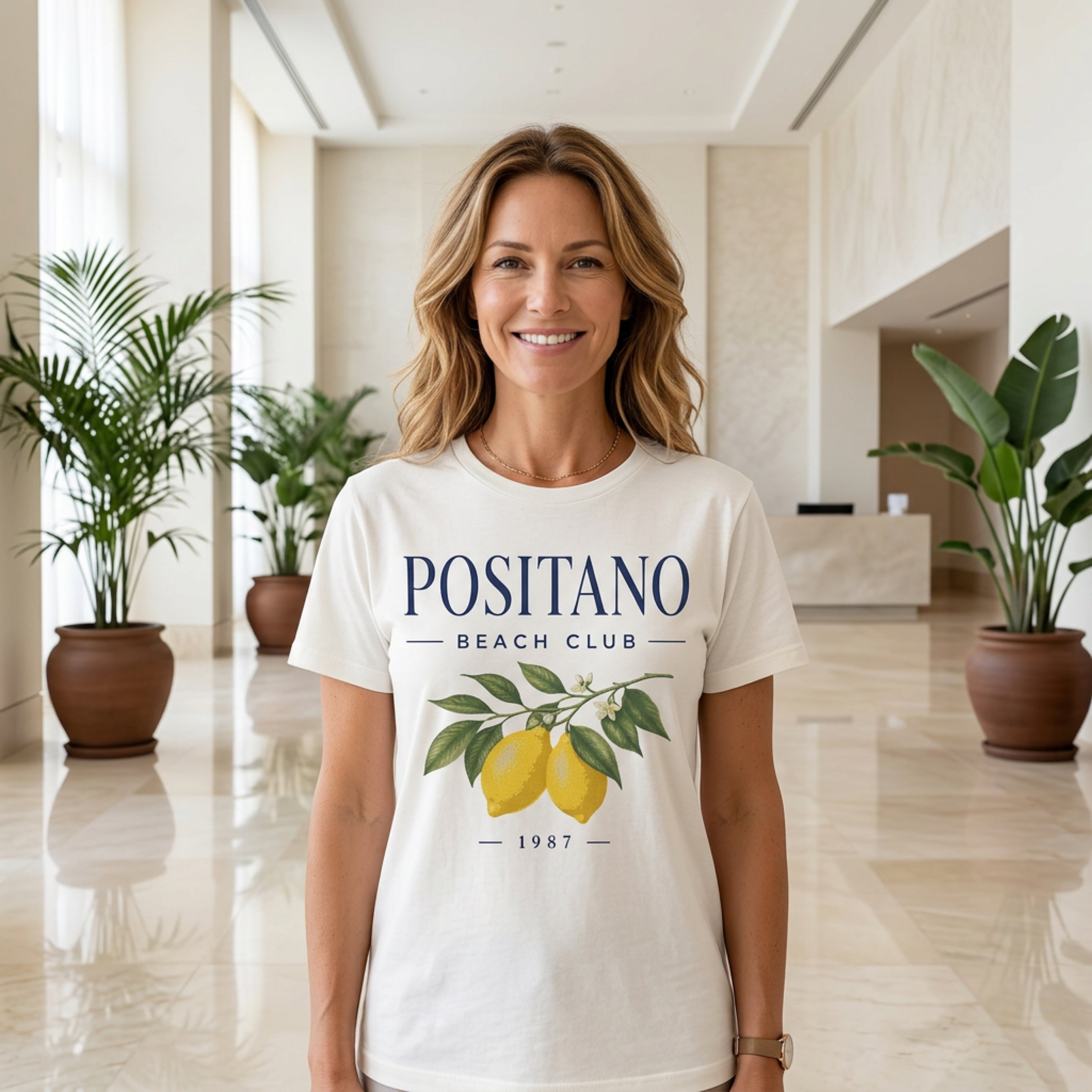 Woman wearing a white Positano Beach Club t-shirt with lemons and 1987.