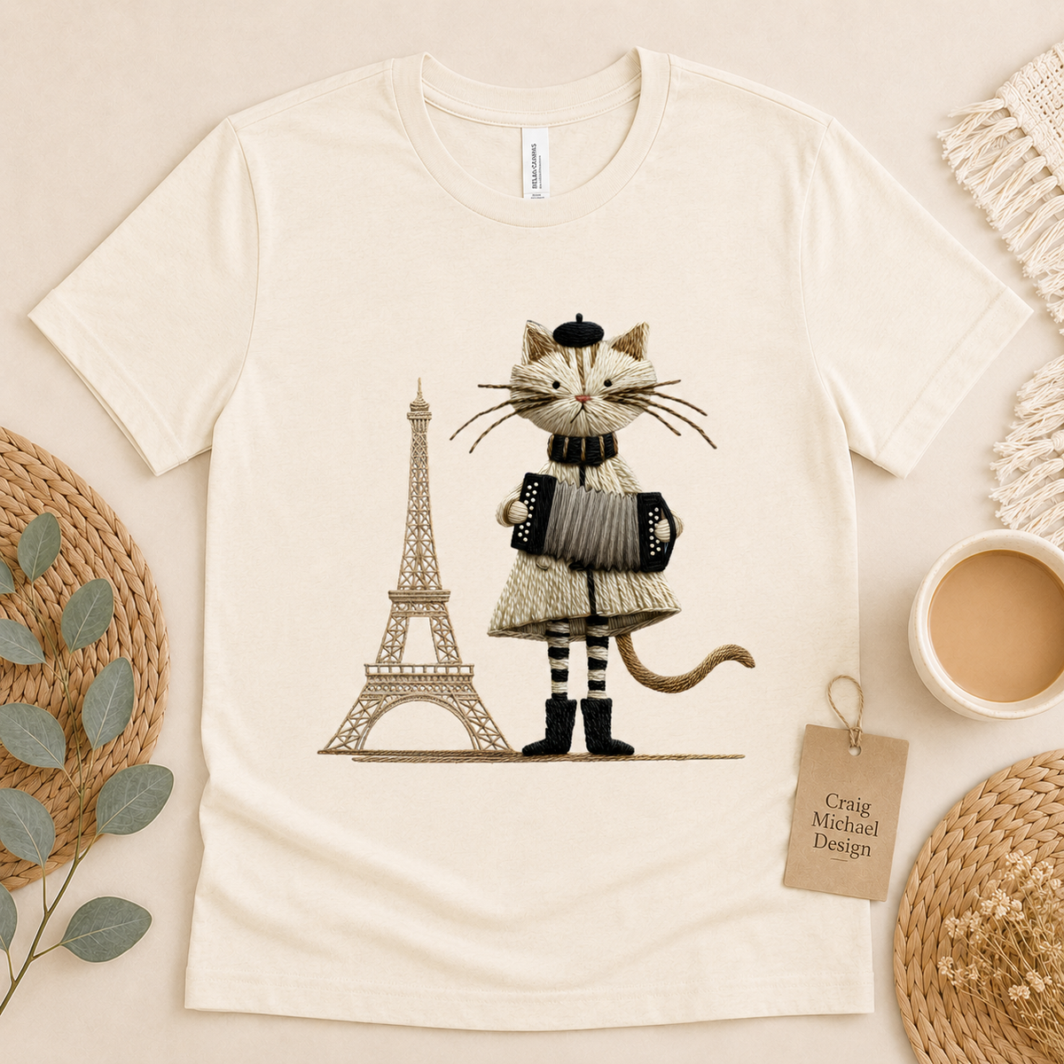 Embroidered cat with accordion and Eiffel Tower graphic on cream t-shirt.