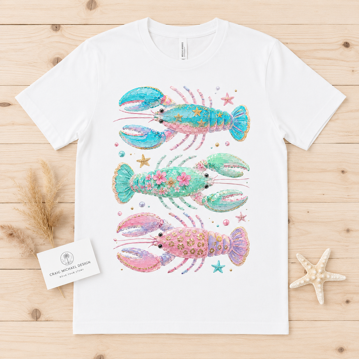 White t-shirt with three stacked watercolor lobsters: blue, green, and pink.