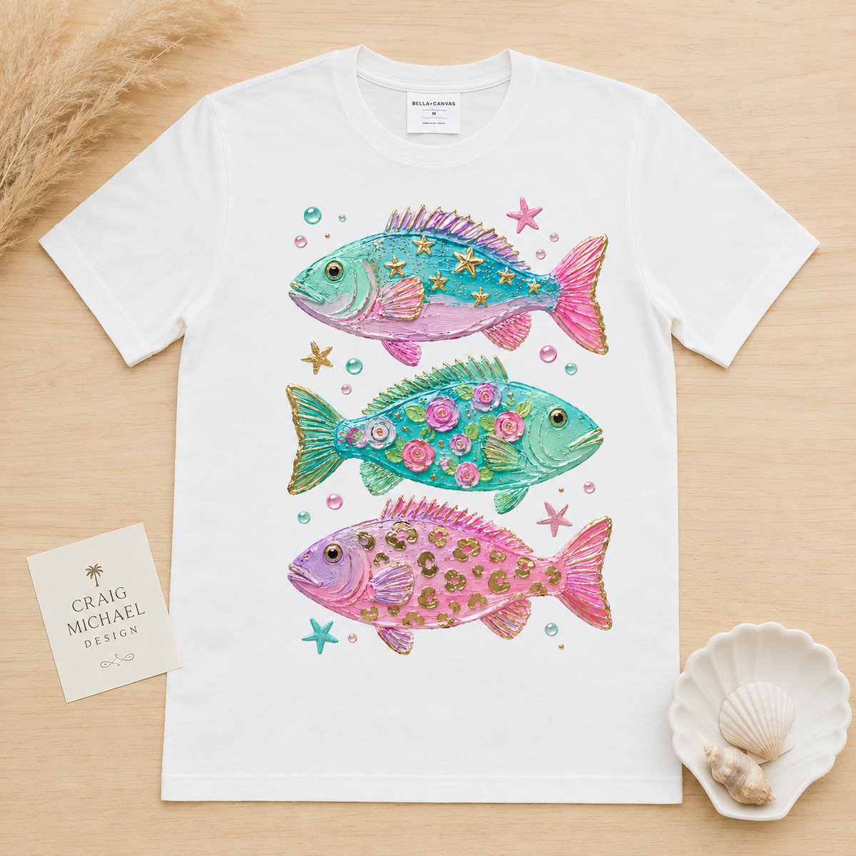 White t-shirt with three colorful, decorative fish in aquamarine, teal, and pink.