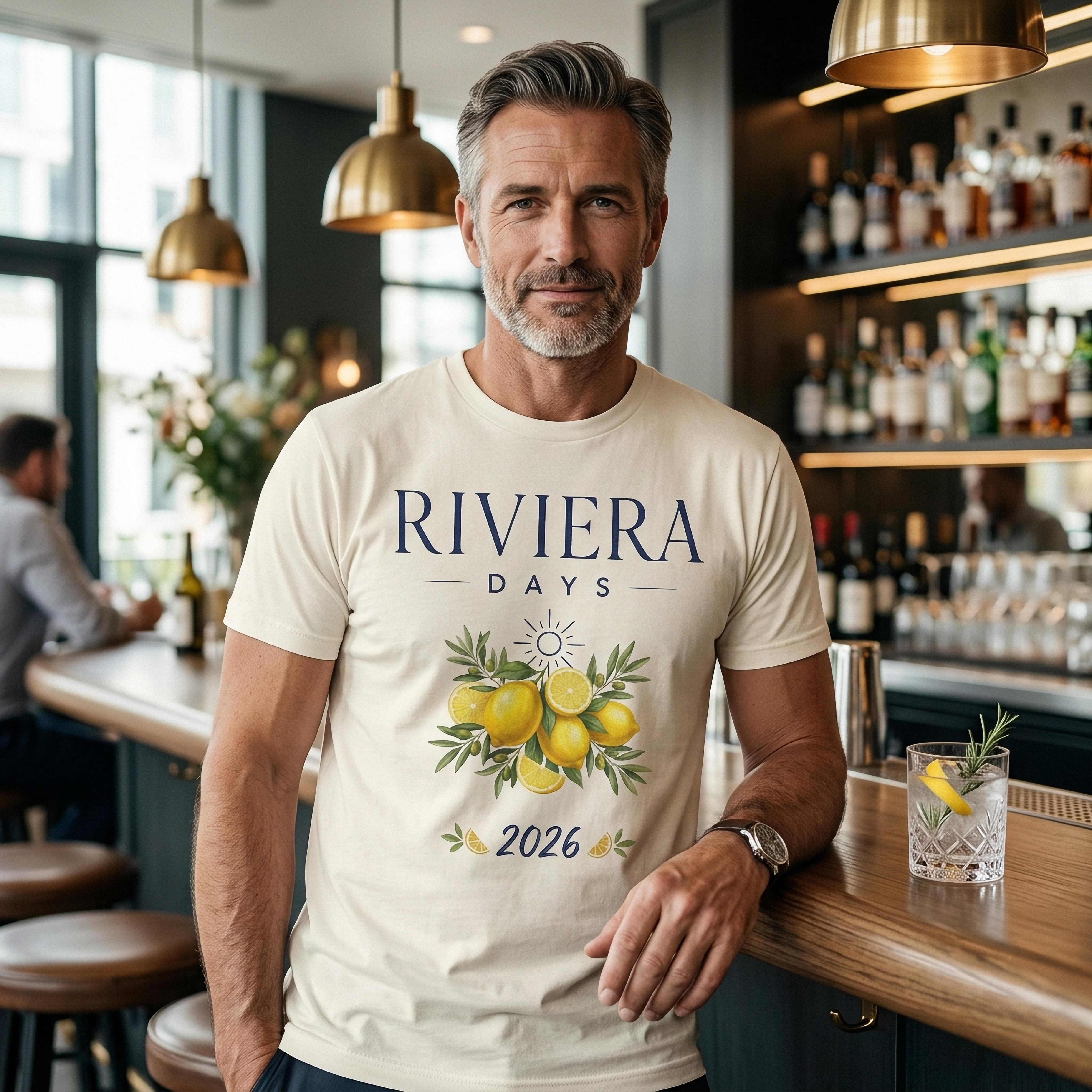 Man wearing "Riviera Days 2026" t-shirt with lemons, leaning on bar.