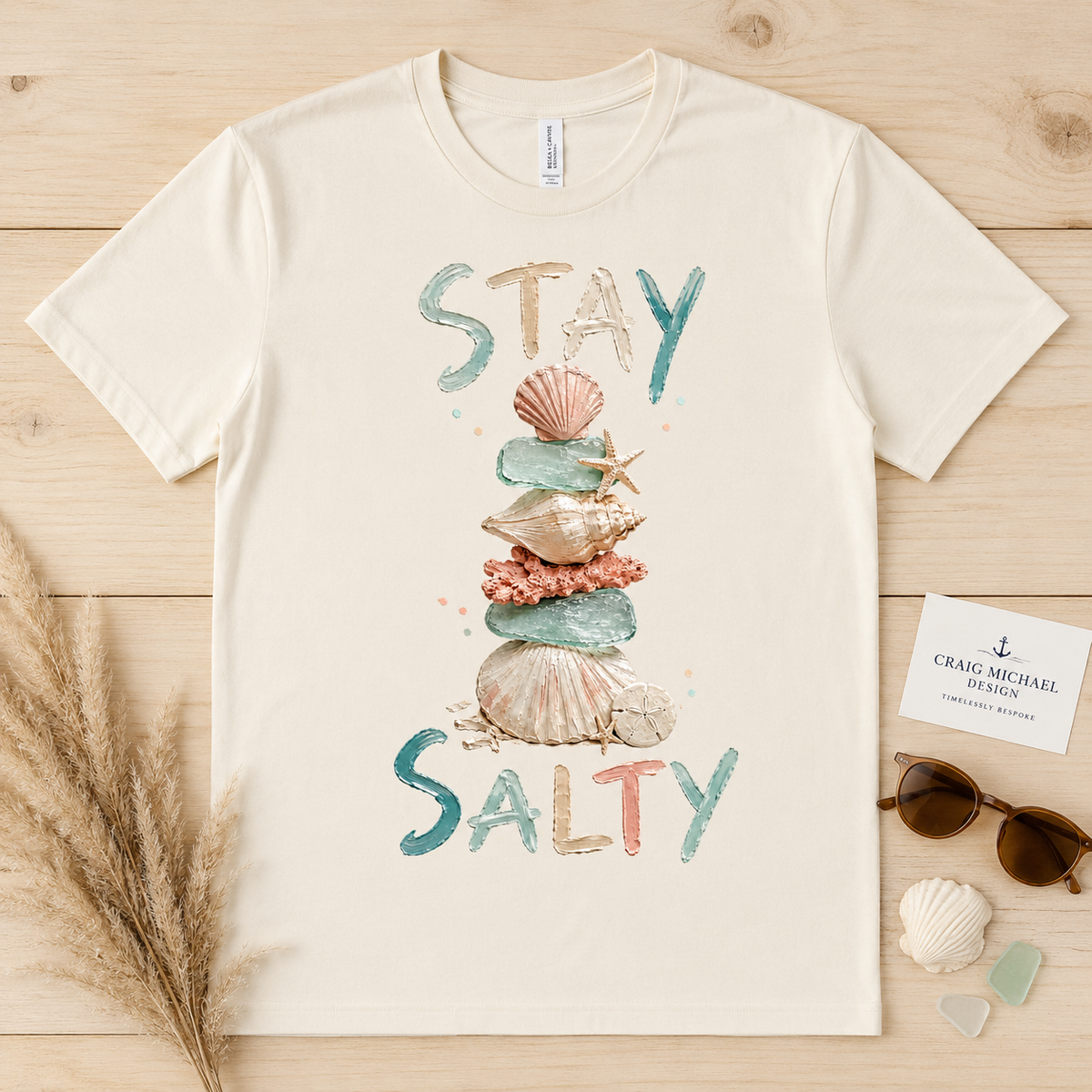 Cream t-shirt with "STAY SALTY" text and stacked seashells.