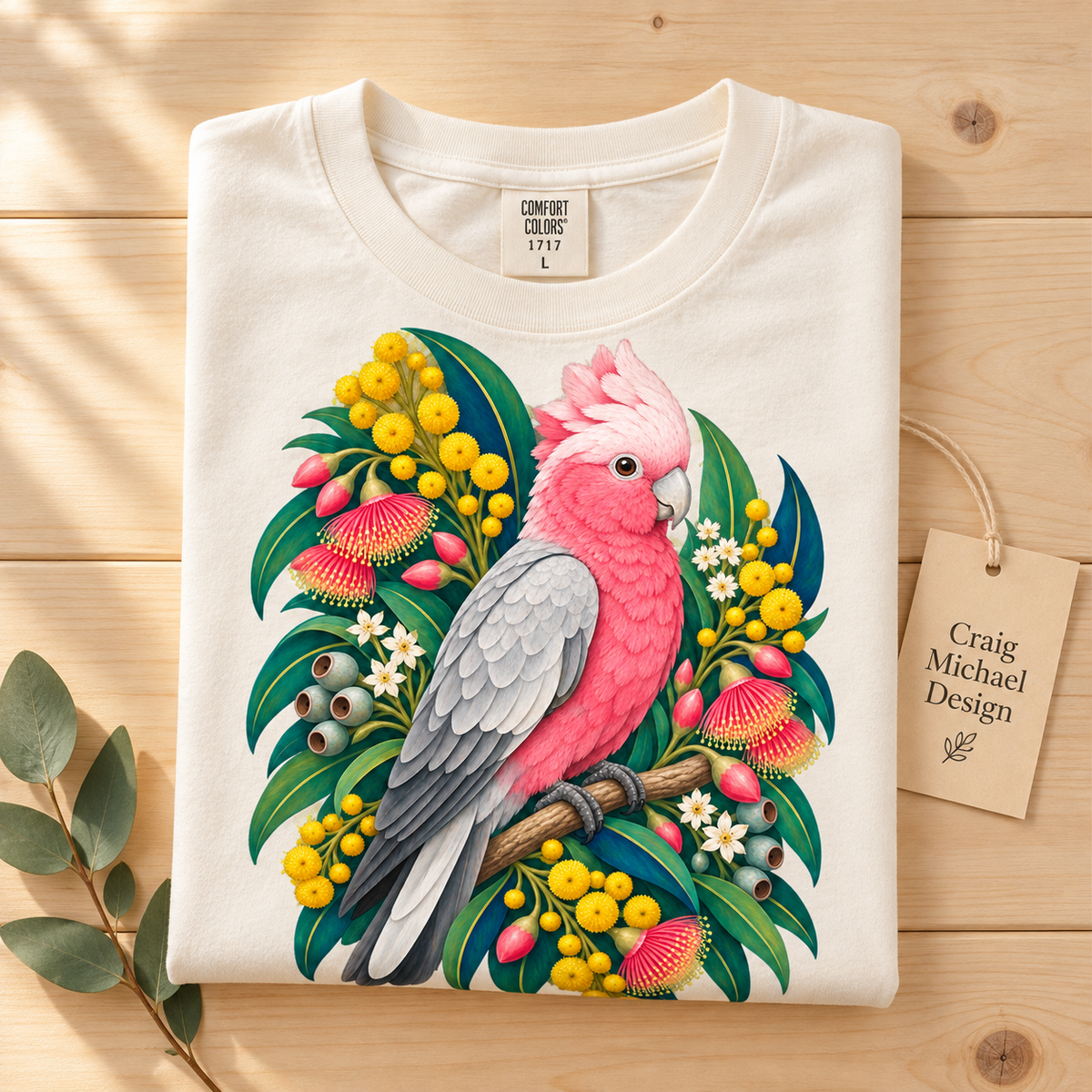 T-shirt with illustration of a pink galah bird on a branch surrounded by Australian flora.