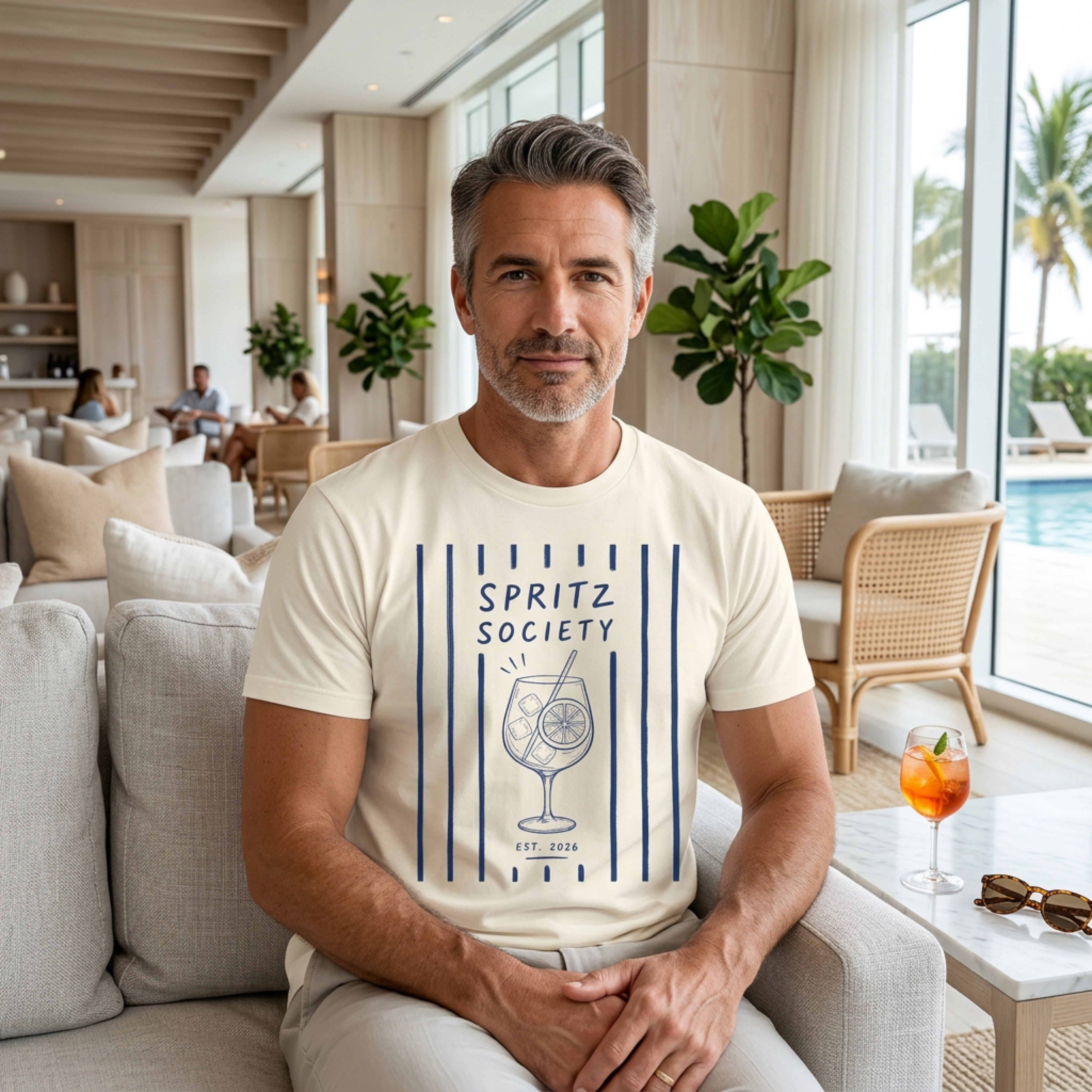 Man in beige t-shirt with Spritz Society logo, sitting in a lounge.