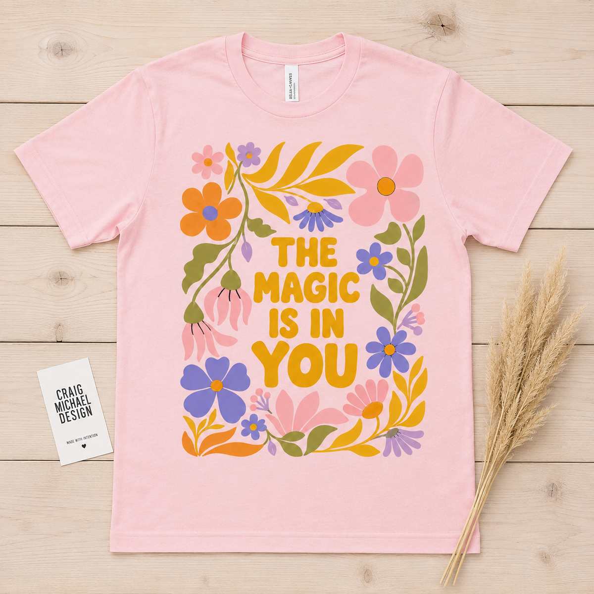 Pink t-shirt with floral design and text "The Magic Is In You".