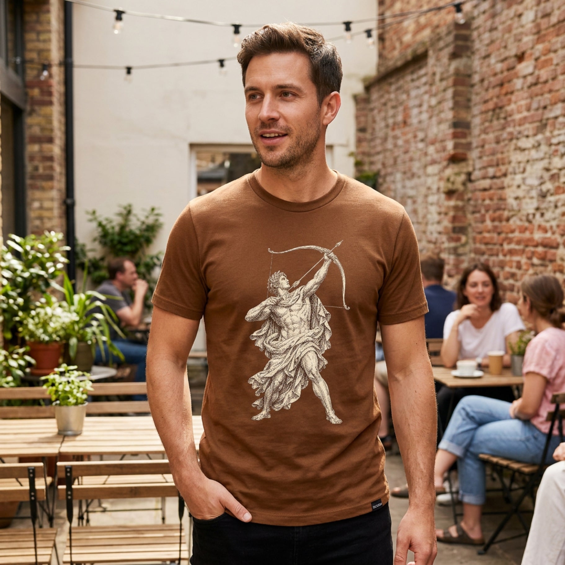 Man wearing brown t-shirt with white classical figure drawing a bow.